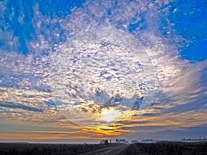 Autumn sunrise with fog. The sun`s rays of the morning sun break through the clouds against the blue sky