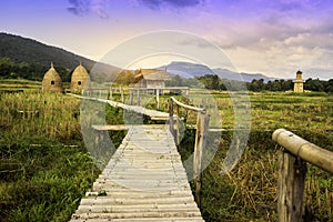 Autumn sunrise in mountainous rural area. Bamboo Walkway and cottage in golden foliage on the meadow in weathered grass