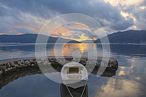 Autumn sunset. Beautiful evening Mediterranean landscape. White fishing boat in small harbor. Montenegro, Kotor Bay