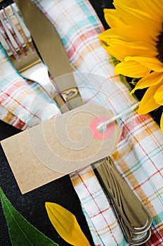 Autumn table place setting with empty tag, cutlery with napkin and sunflower