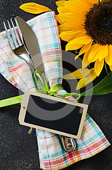 Autumn table place setting with empty tag, cutlery with napkin and sunflower