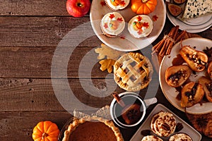 Autumn table scene corner border of pies, appetizers and desserts. Top view over a wood background with copy space.