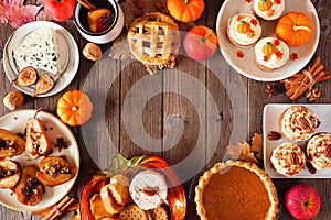 Autumn table scene frame of pies, appetizers and desserts. Top view over a wood background with copy space.