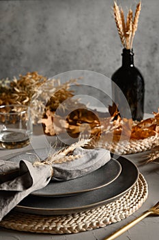 Autumn table setting with dry yellow oak leaves, fall decoration on grey table. Thankisgiving day