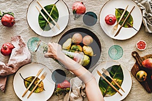 Autumn table setting and female hand pouring drink to glass