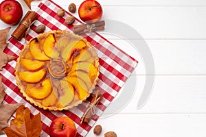 Autumn thankgiving pie on white wooden board decorated with dry leaves and cinnamon sticks