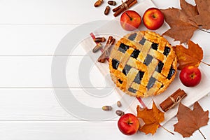 Autumn thankgiving pie on white wooden board decorated with dry leaves and cinnamon sticks