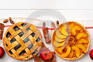 Autumn thankgiving pies on white wooden board decorated with dry leaves and cinnamon sticks