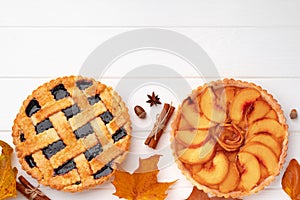 Autumn thankgiving pies on white wooden board decorated with dry leaves and cinnamon sticks