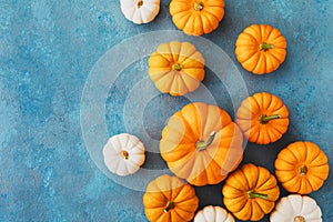 Autumn Thanksgiving background. Heap of white and orange pumpkins on blue table top view