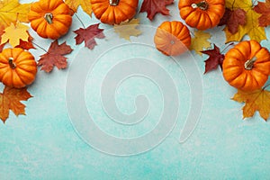 Autumn Thanksgiving background. Pumpkins and maple leaves on turquoise table top view