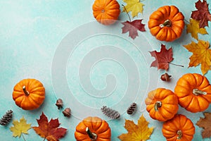 Autumn Thanksgiving background. Pumpkins and maple leaves on turquoise table top view