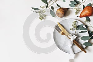 Autumn thanksgiving table place setting. Golden cutlery, porcelain plate, berry eucalyptus leaves and branches, silk photo