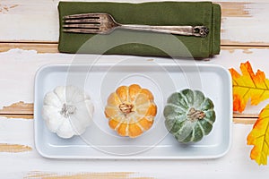 Autumn Thanksgiving table setting for dinner with plate, knife, fork decorated pumpkins. Top view