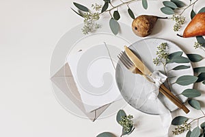 Autumn Thanksgiving table setting. Golden cutlery, plate, berry eucalyptus leaves, branches. Blank greeting card