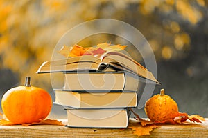 Autumn thematic reading. Books and pumpkins set in autumn garden .Start school and college season concept.Books on the