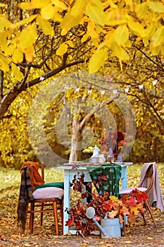 Autumn themed holiday table setting arrangement for a seasonal party, cups, apples, candles, field flowers.