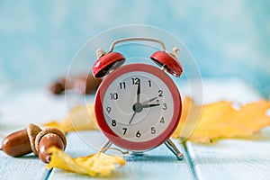 Autumn time change concept - red alarm clock on wood background