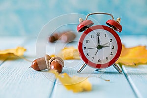 Autumn time change concept - red alarm clock on wood background