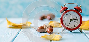 Autumn time change concept - red alarm clock on wood background