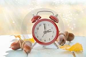 Autumn time change concept - red alarm clock on wood background