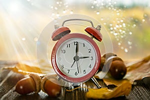 Autumn time change concept - red alarm clock on wood background