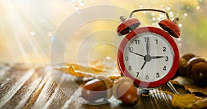 Autumn time change concept - red alarm clock on wood background