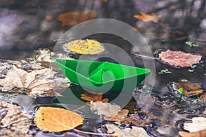 Autumn time. Paper boat and fallen dry leaves on the water surface. Beautiful nature background. Goodbye autumn.