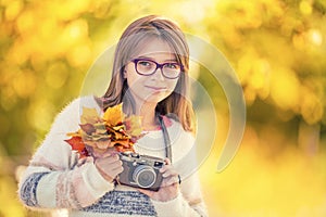 Autumn time. The teenage attractive cute young girl with autumn bouquet and retro camera. Young girl photographer autumn season