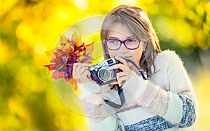 Autumn time. The teenage attractive cute young girl with autumn bouquet and retro camera. Young girl photographer autumn season