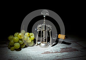 Autumn is the time for winemaking. Composition with a bottle of wine, a bunch of white grapes and a corkscrew on a wooden