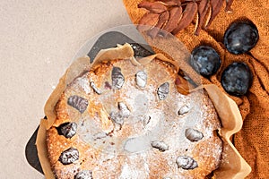 Autumn traditional bakery, Thanksgiving day treat. Pie, cake with plum, cinnamon and sugar powder on orange knitted