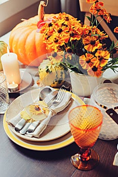 Autumn traditional seasonal table setting at home with pumpkins, candles and flowers