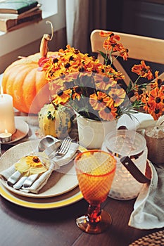 Autumn traditional seasonal table setting at home with pumpkins, candles and flowers