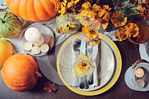 Autumn traditional seasonal table setting at home with pumpkins, candles and flowers