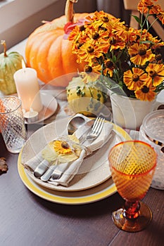 Autumn traditional seasonal table setting at home with pumpkins, candles and flowers