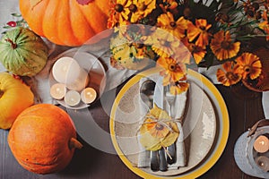 Autumn traditional seasonal table setting at home with pumpkins, candles and flowers