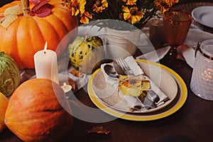 Autumn traditional seasonal table setting at home with pumpkins, candles and flowers