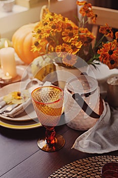 Autumn traditional seasonal table setting at home with pumpkins, candles and flowers