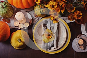 Autumn traditional seasonal table setting at home with pumpkins, candles and flowers