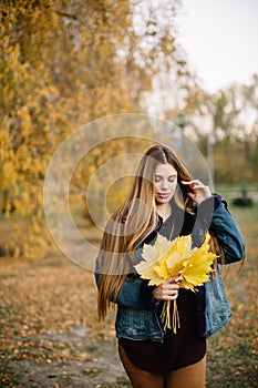 Autumn trend. Beautiful woman fashion model with long hair having fun in fall park outdoors. Pretty tenderness model