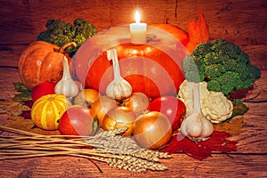 Autumn vegetables on a wooden background with a candle.