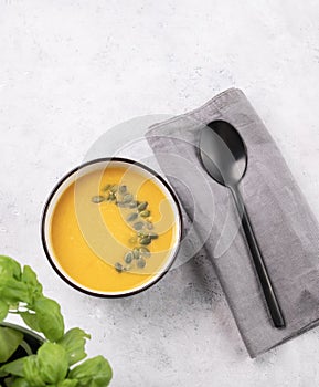 Autumn vegetarian pumpkin soup with cream and seeds on white  background with fresh herbal and spoon