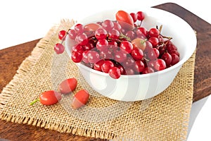 Autumn viburnum berries and rose hips lie in a white bowl, isolated white background.