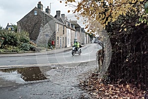Autumn view of a commuter seen riding his Scooter during wet weather.