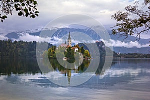 Autumn view of the historical church on the island in Lake Bled before snow capped Alps