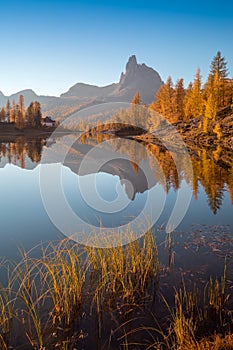 Autumn view of Lake Federa in Dolomites at sunset. Fantastic autumn scene with blue sky, majestic rocky mount and colorful trees