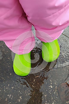 Autumn walk of a child through puddles on asphalt