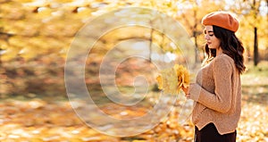 Autumn walk. Woman portrait. Dreaming girl holding maple leaves bouquet. Women enjoying fall nature. Banner.