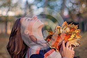 Autumn warm day.Girl on an autumn day in the park on a warm fall day with autumn leaves in her hands